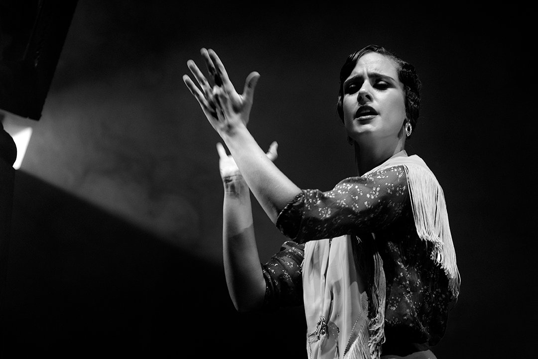 Una bailarina levanta la mano ante el público.